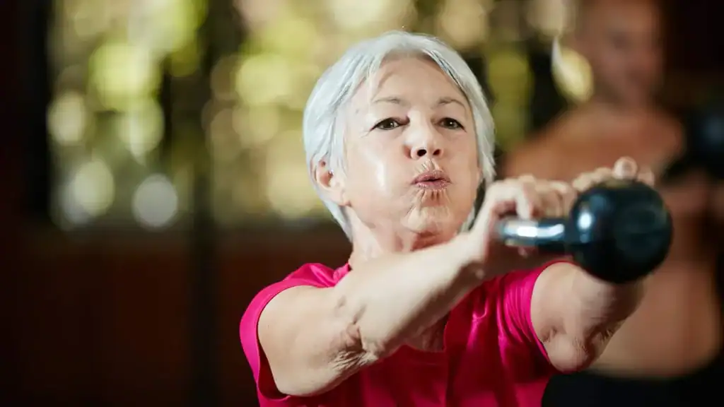 Older woman doing weight training Teddington to help her strength and longevity 
