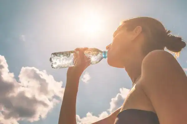 Hydration: The Secret Ingredient for a Toned Stomach and Enhanced Fitness 3 Image of woman drinking water to hydrate Teddington after run.