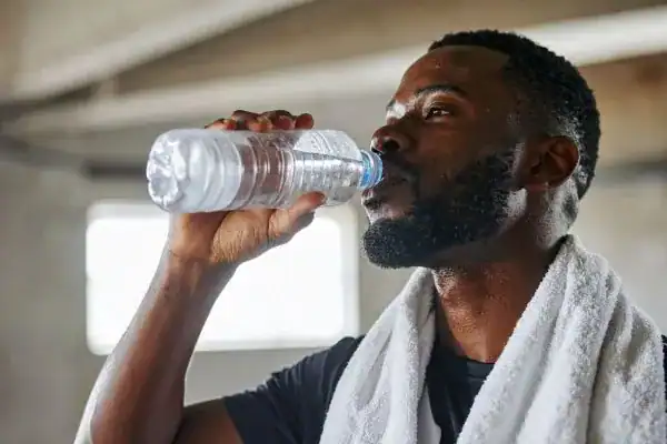 Hydration: The Secret Ingredient for a Toned Stomach and Enhanced Fitness 1 Image of man drinking water to improve hydration Teddington after work out.
